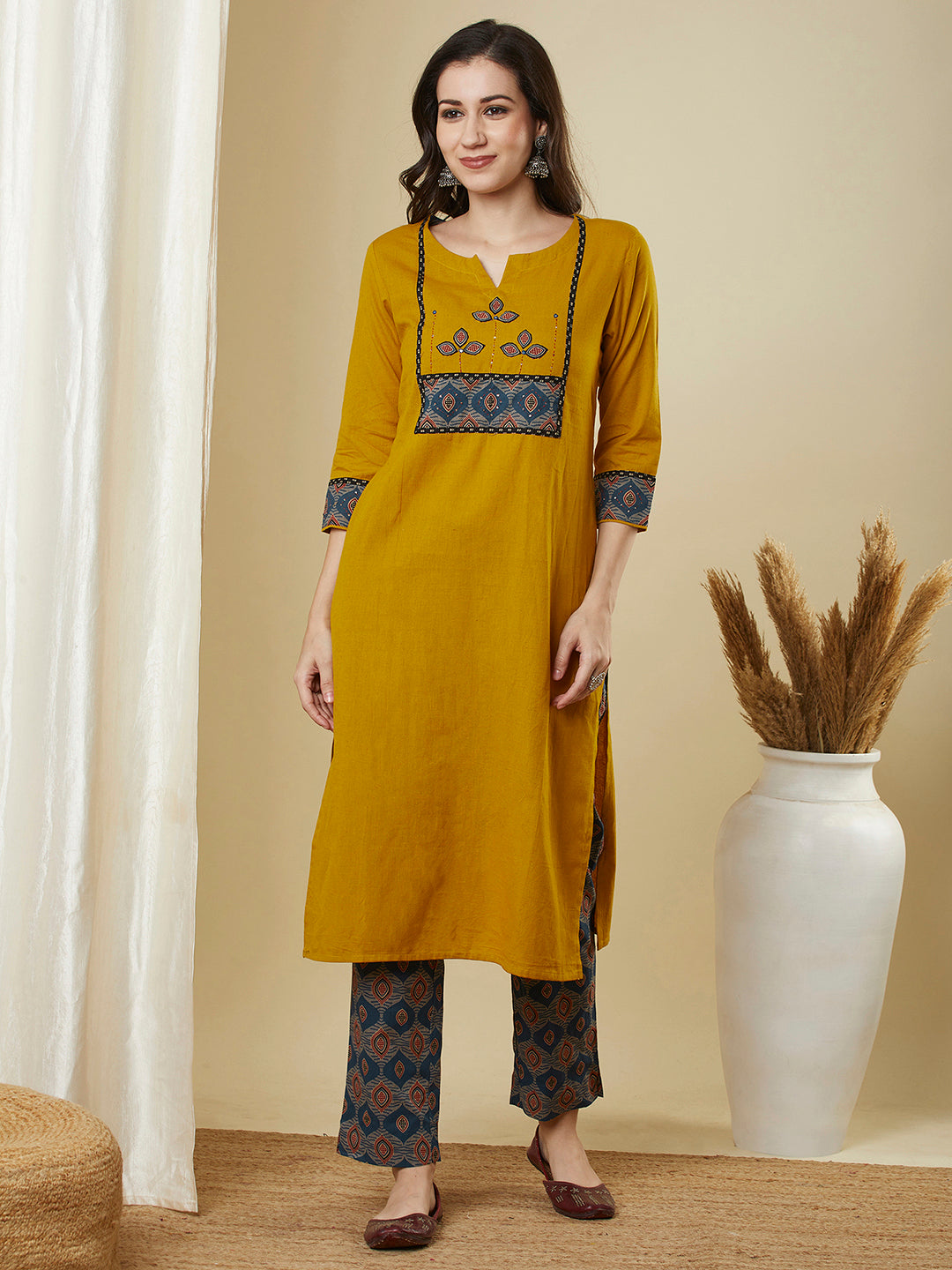 A mustard kurta suit set featuring a mix-match yoke and hand applique