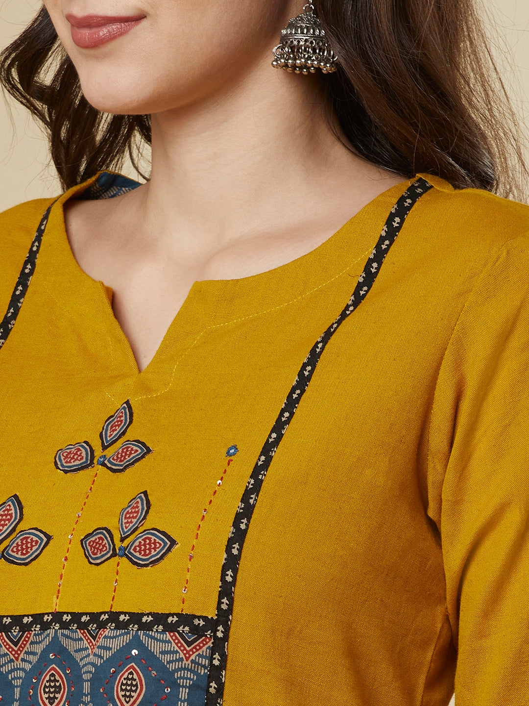 A mustard kurta suit set featuring a mix-match yoke and hand applique