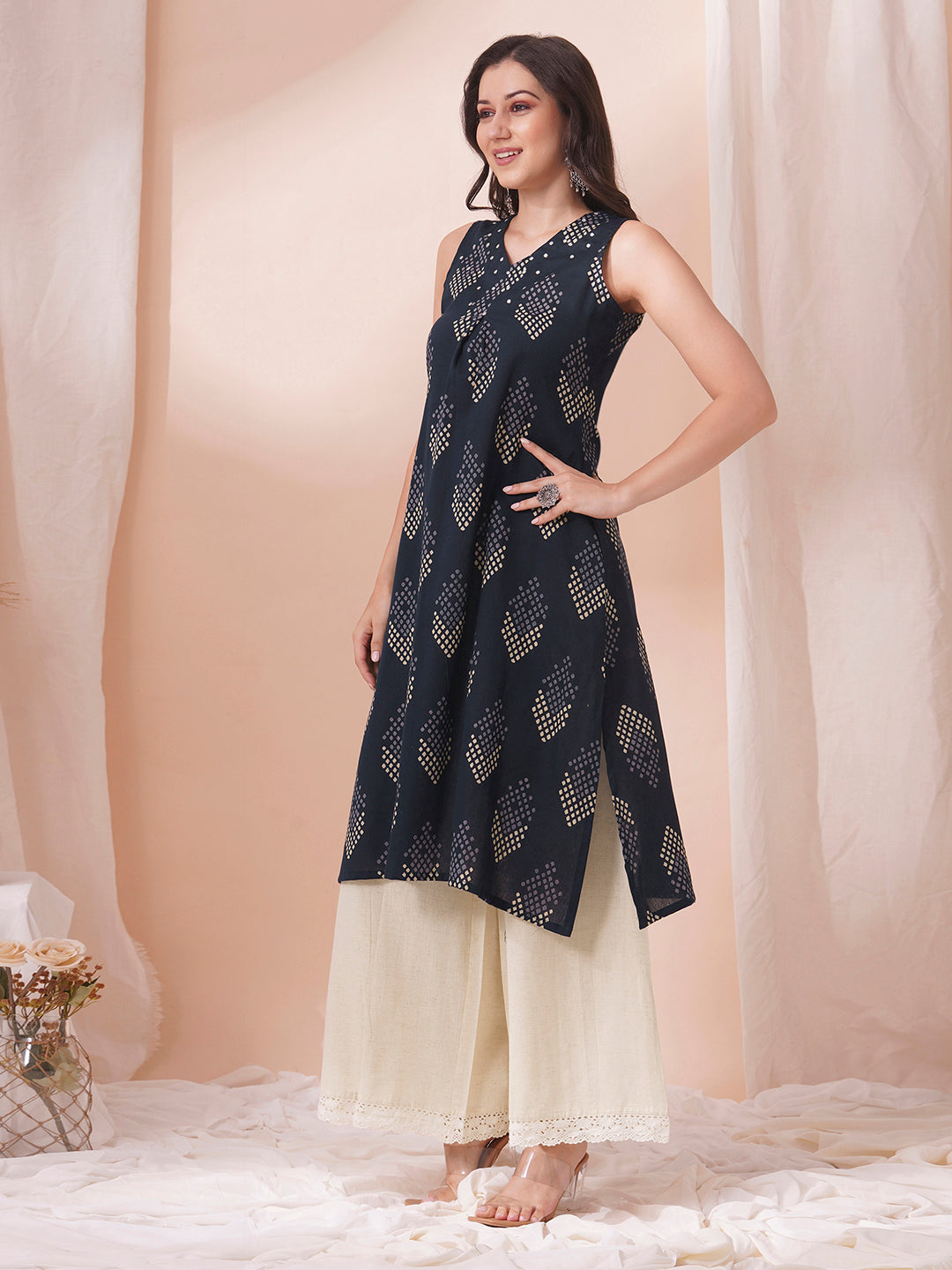 A centre box pleated sleeveless kurta with mirrorwork detailing on the neck.