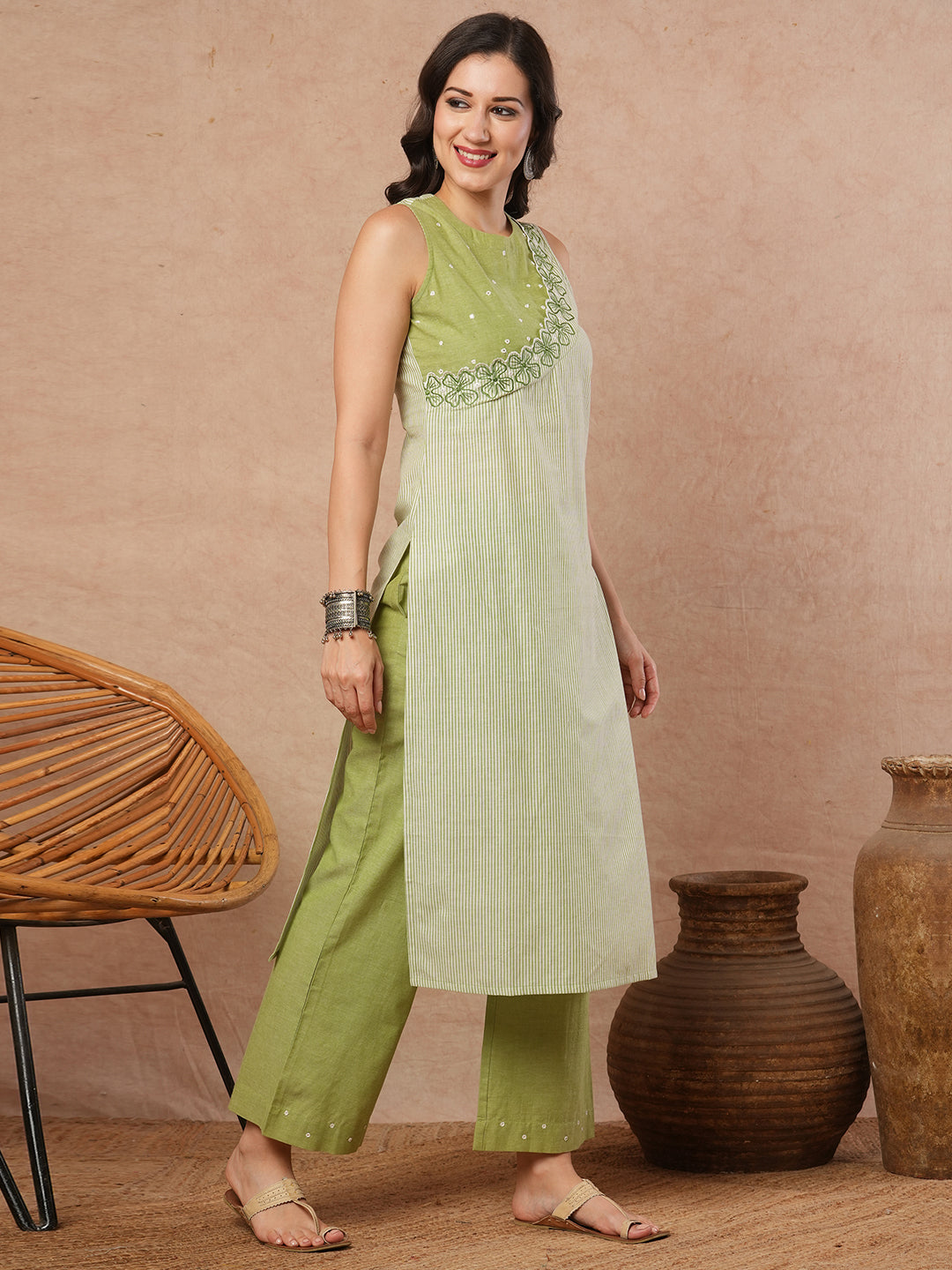 Sleeveless straight kurta with cutwork neckline and mirror work.