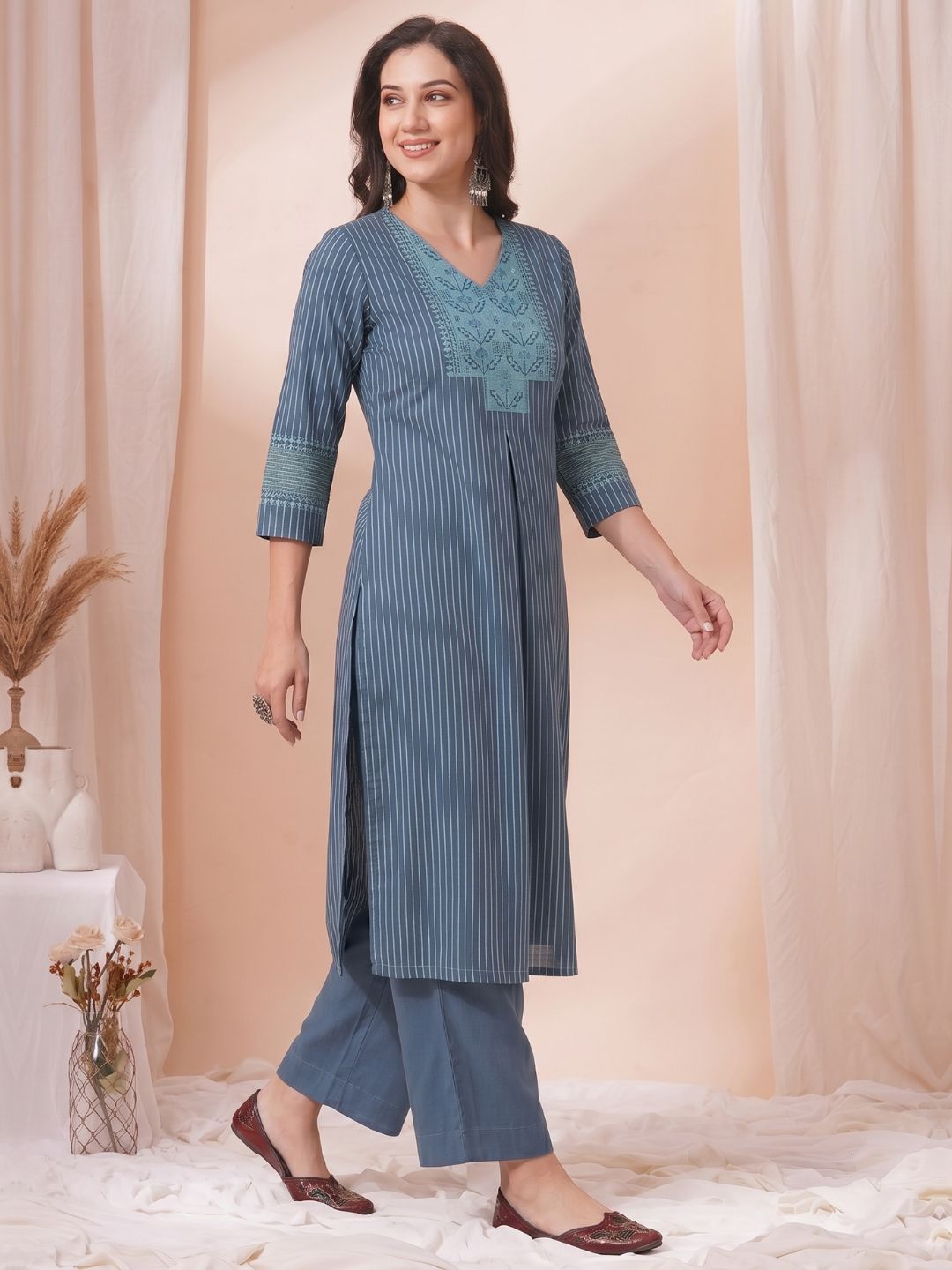 Woman wearing a blue striped kurta with embroidery in a neutral setting