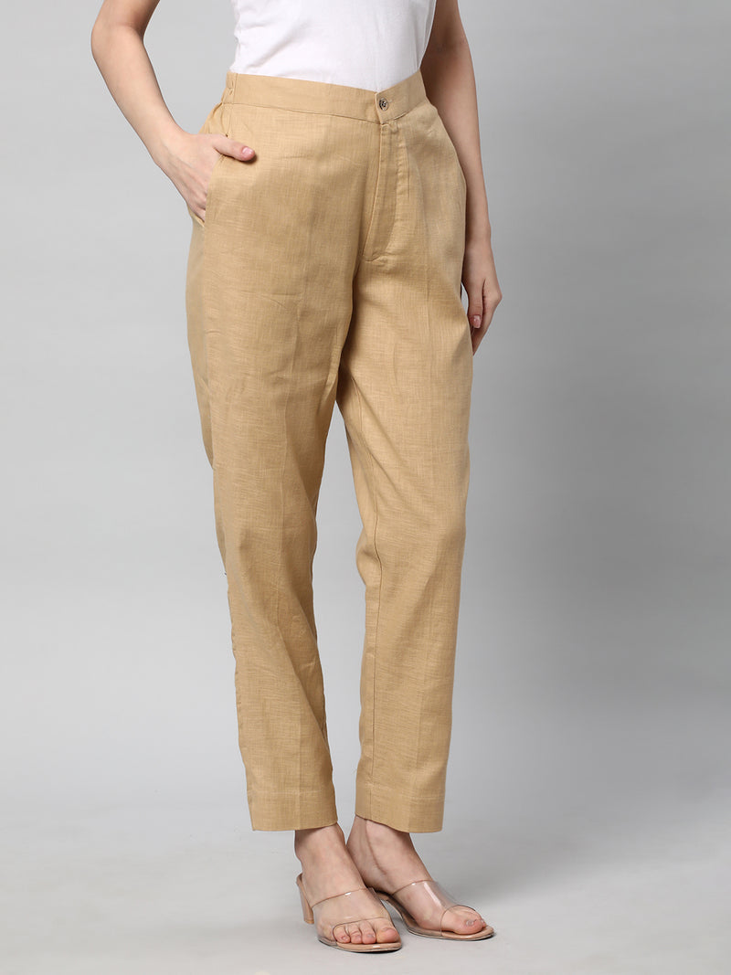 A beige ankle length cotton linen pant with plain belt in front.