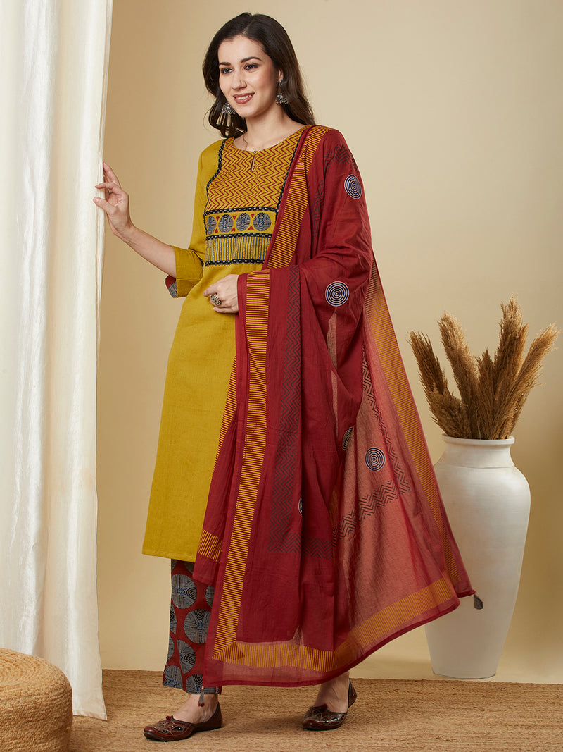 Mustard kurta suit set is paired with a printed bottom and a contrast color block-printed dupatta.