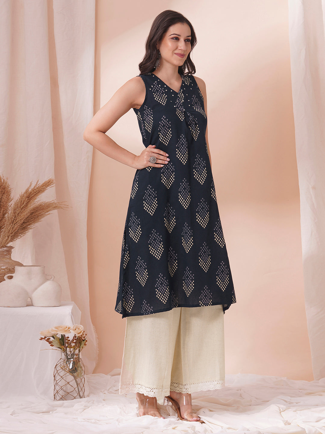 A centre box pleated sleeveless kurta with mirrorwork detailing on the neck.