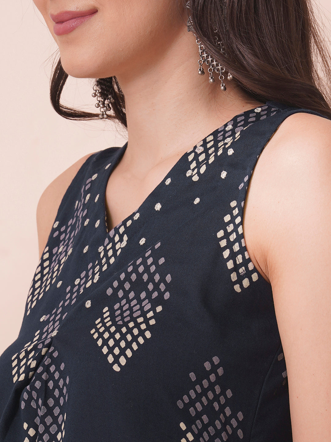 A centre box pleated sleeveless kurta with mirrorwork detailing on the neck.