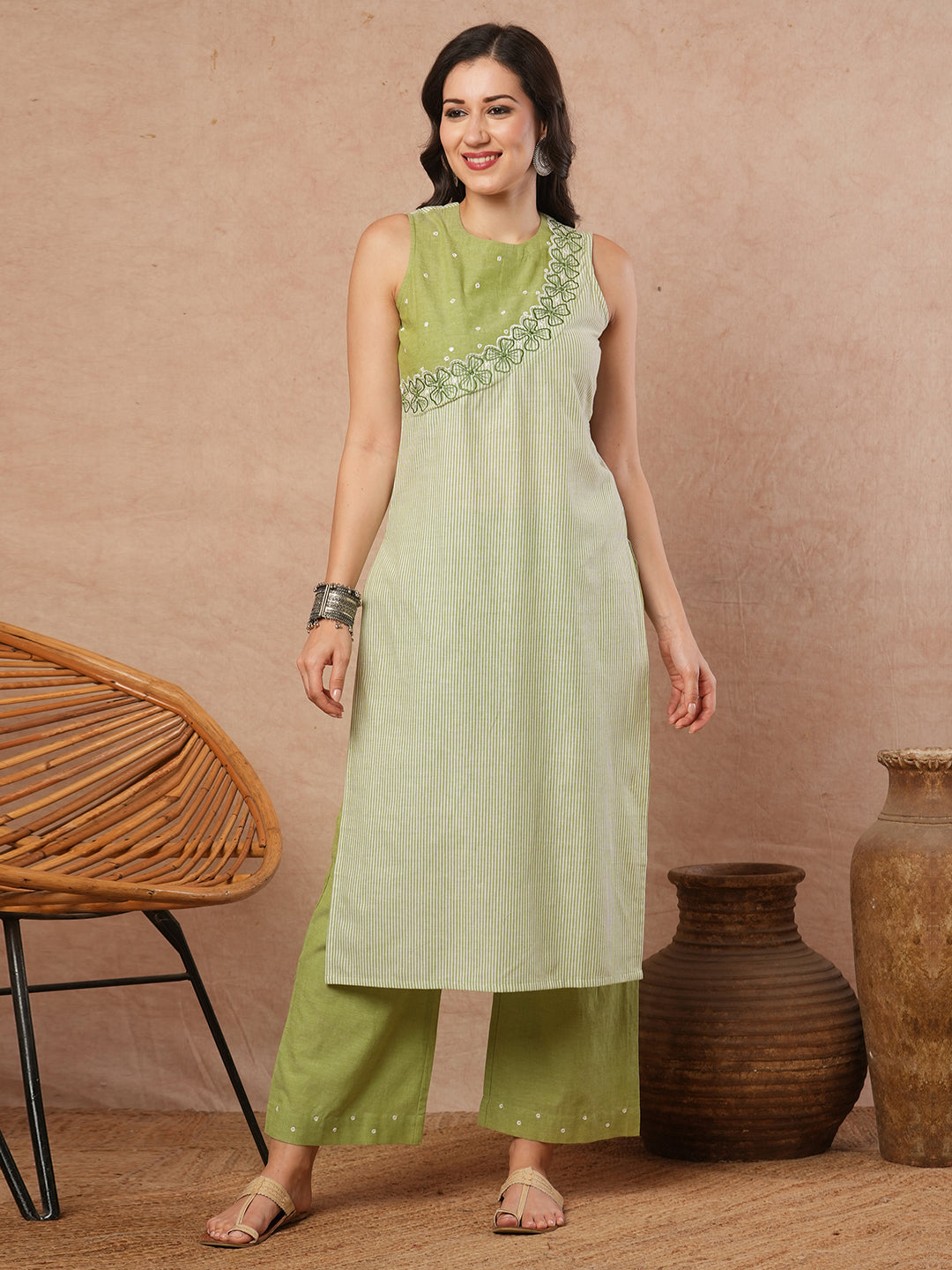 Sleeveless straight kurta with cutwork neckline and mirror work.