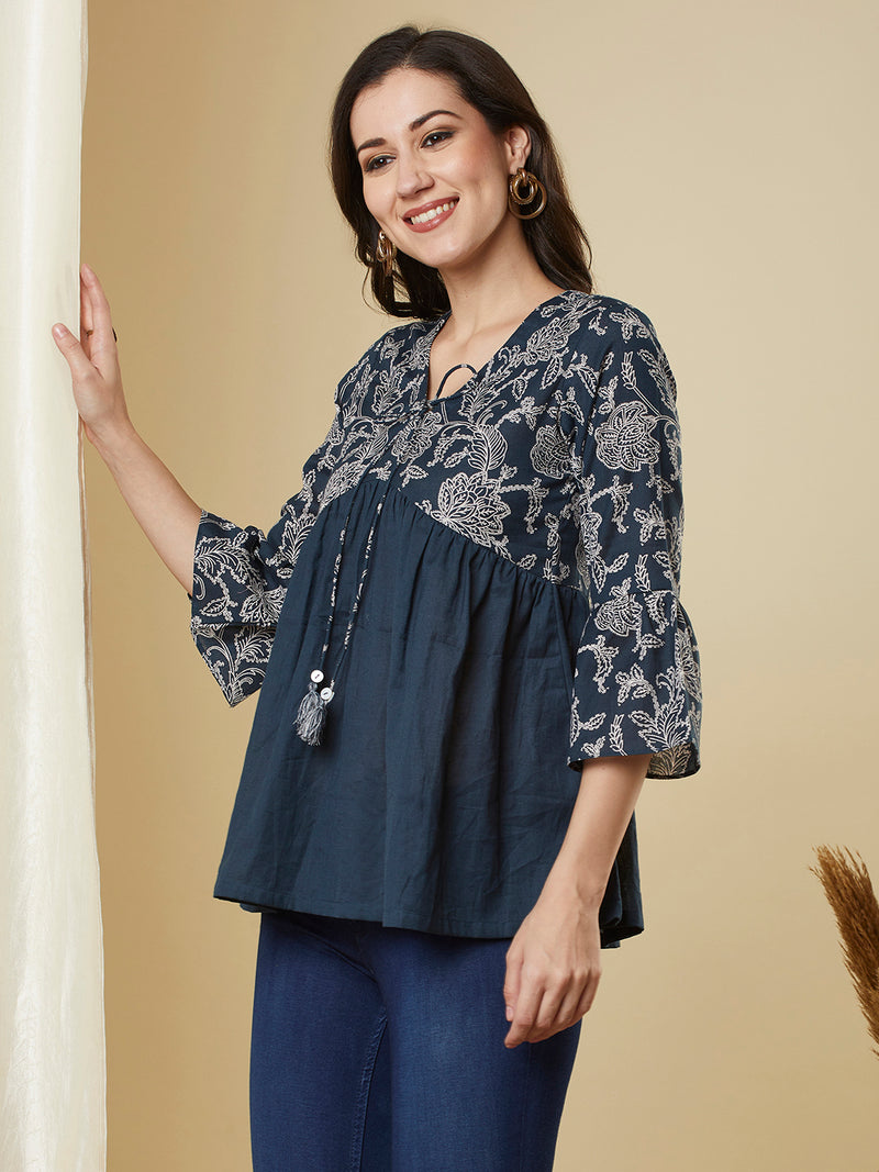 A navy blue shaped waist top with printed yoke and bell sleeves and gathered solid flare.