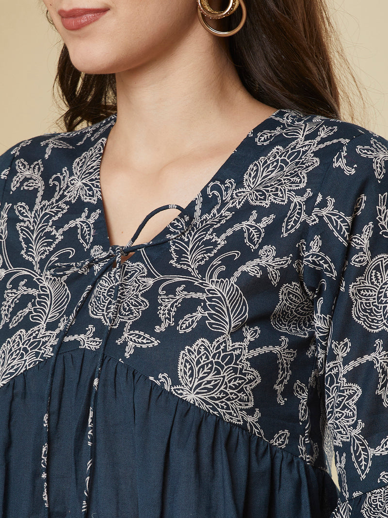 A navy blue shaped waist top with printed yoke and bell sleeves and gathered solid flare.